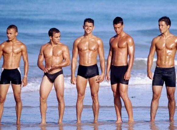 muži na pláži so zväčšenými kohútmi